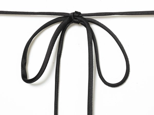 Detailed close-up of a black satin ribbon tied into a bow on a stylish silk-texture dress