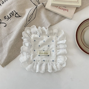 Detail of white lace coaster with blue heart patterns and a woven Sozakka label