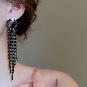Detail of elegant black long tassel earrings with sparkling rhinestones on model