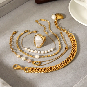French style gold pearl jewelry set with heart and shell charms on grey velvet tray