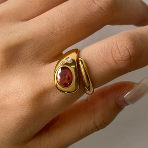 Détail d'une bague dorée vintage avec grande pierre rouge ovale et diamants d'accent