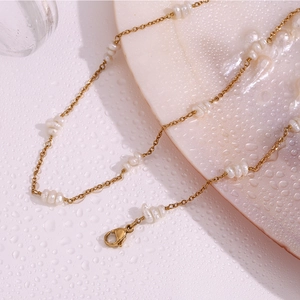 Détail macro d'une chaîne perlée en or 18 carats avec perles d'eau douce sur fond de coquillage