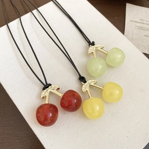 Detail of colorful cherry pendants in red, yellow and green with elegant gold leaf accents