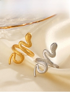 Detail of snake-shaped rings in gold and silver finish with textured scales on satin