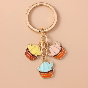 Detailed close-up of three colorful enamel cactus charms on a golden metal keychain
