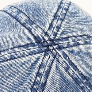 Gros plan de la couronne du chapeau en denim bleu délavé montrant coutures et tissu