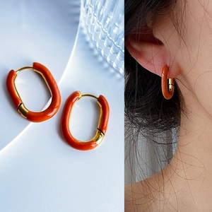 Detail view of retro U-shaped earrings with vibrant orange enamel and 18k gold plating