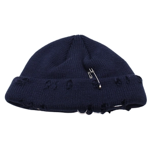 Dettaglio del cappello miki blu scuro con fori usurati, spilla in metallo e anelli decorati
