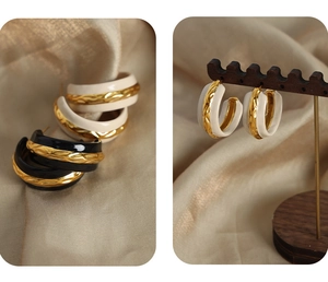 Close-up of vintage C-shape gold-plated earrings with black and beige enamel glaze