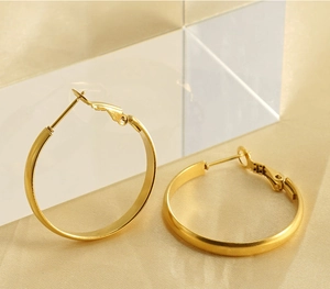 Close-up of gold minimalist hoop earrings on silk background with soft lighting