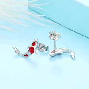 Detailed view of silver koi fish earrings with red enamel and zircon on a blue box