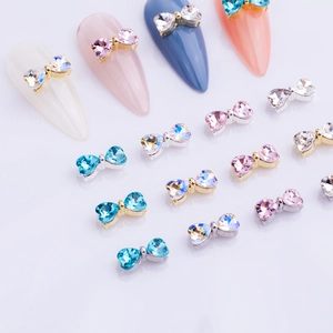 Macro detail of heart-shaped crystal bow nail charms with colorful rhinestones