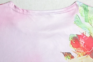 Detailed close-up of crew neck with floral print and double-stitched sewing finish