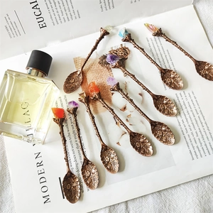 Detail of vintage bronze branch spoons with colorful crystal stone tops and floral engraving