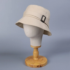 Detail of beige cotton bucket hat featuring a decorative belt with rectangular buckle