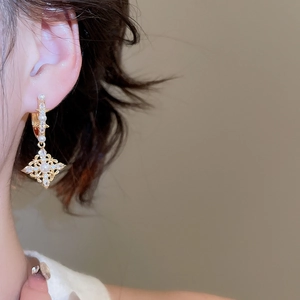 Close-up of model wearing 18K gold-plated diamond and pearl rhombus drop earrings