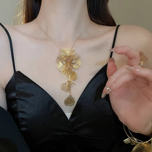Detail of gold floral necklace with hollow petals and central sparkling rhinestones