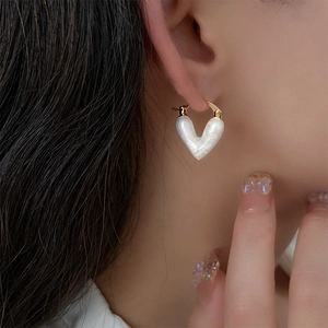 Vue rapprochée d'une boucle d'oreille cœur en nacre blanche avec fermoir doré