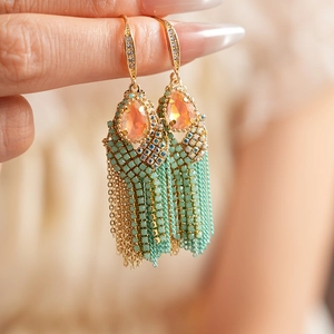 Close-up of bohemian tassel earrings with orange teardrop stones and turquoise beadwork