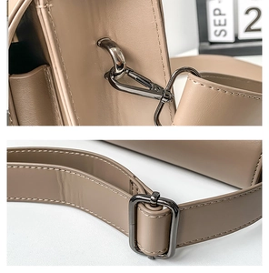 Detail of premium khaki leather bag featuring metal hooks and adjustable shoulder strap buckle