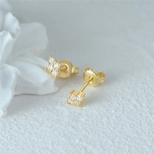 Macro view of gold stud earrings featuring four round crystals and butterfly backs