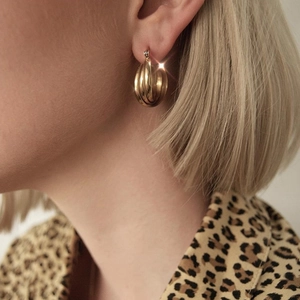 Boucles d'oreilles créoles dorées torsadées au design spirale portées par un mannequin