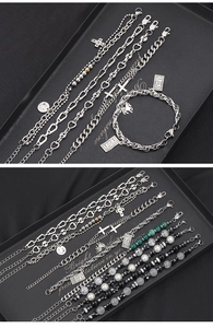 Detail of beaded bracelets with heart links, cross charms, and multicolored stones