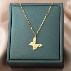 Detail of a gold double-layer butterfly pendant on a green jewelry box with silk ribbon
