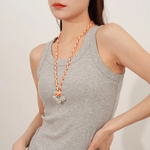 Detail of silver floral pendant necklace with colorful braided rope on model