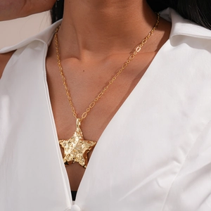 Détail macro du pendentif étoile de mer doré avec texture martelée et strass brillants