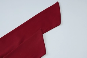 Detail of red fabric strap showing fine stitching and polyester texture on light background
