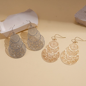Boucles d'oreilles mandala évidées en or et argent sur un présentoir texturé chic