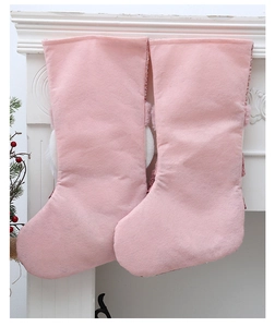 Detailansicht rosa Plüsch-Weihnachtssocken mit Pailletten am weißen Kamin hängend