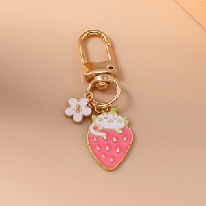 Cute pink strawberry keychain with a white cat and small flower on a golden ring