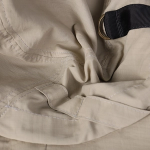 Close-up of khaki ripstop fabric showing durable double stitching and metal D-ring detail