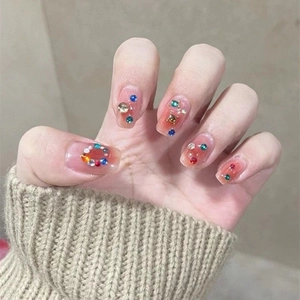Detail of cat eye flower press-on nails with colorful rhinestones and pink gradient