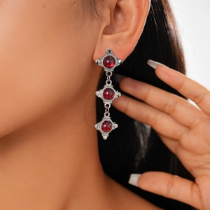 Detail of red resin drop earrings featuring ornate silver frames in a vintage bohemian style