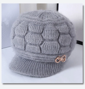 Detail of grey winter knit hat for elderly women showing thick wool texture and golden bow