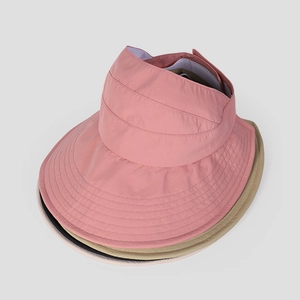 Detail of pink, beige, and black wide brim sun visors stacked showing stitching and fabric