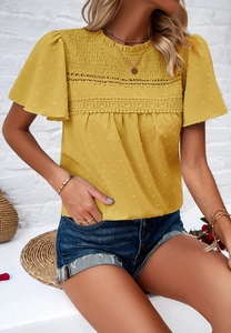 Detailed close-up of yellow polka dot top with lace hollow out and pleated texture