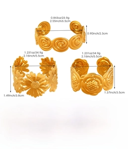 Detailed view of three gold stainless steel cuffs with flower and spiral designs