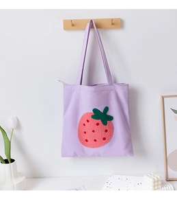 Close-up of a purple canvas tote bag featuring a cute 3D plush strawberry embroidery