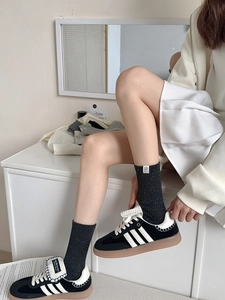 Detail of grey knitted mid-calf socks paired with black sneakers and casual outfit