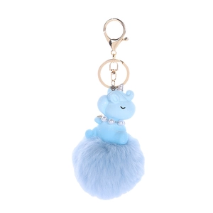 Detail view of a blue plush unicorn keychain with fluffy ball and golden metal ring