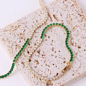 Detailed macro view of gold tennis bracelet with white and emerald green zircon stones