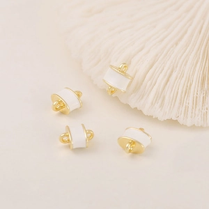 Detailed view of four golden bead charms with white enamel on a clean white surface