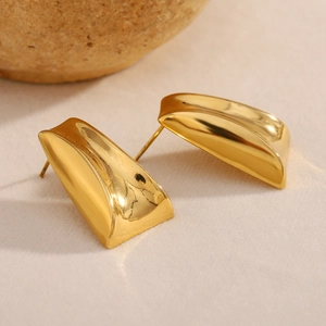 Detail shot of 18K gold plated trapezoid stud earrings on beige textured surface