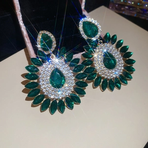 Detailed macro of sparkling emerald teardrop earrings on black velvet display case