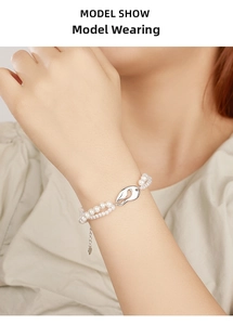 Dettaglio di un elegante bracciale a doppio filo di perle con ciondolo a chicco d'argento
