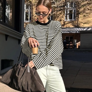 Detail eines locker sitzenden schwarz-weiß gestreiften Langarmshirts mit brauner Handtasche